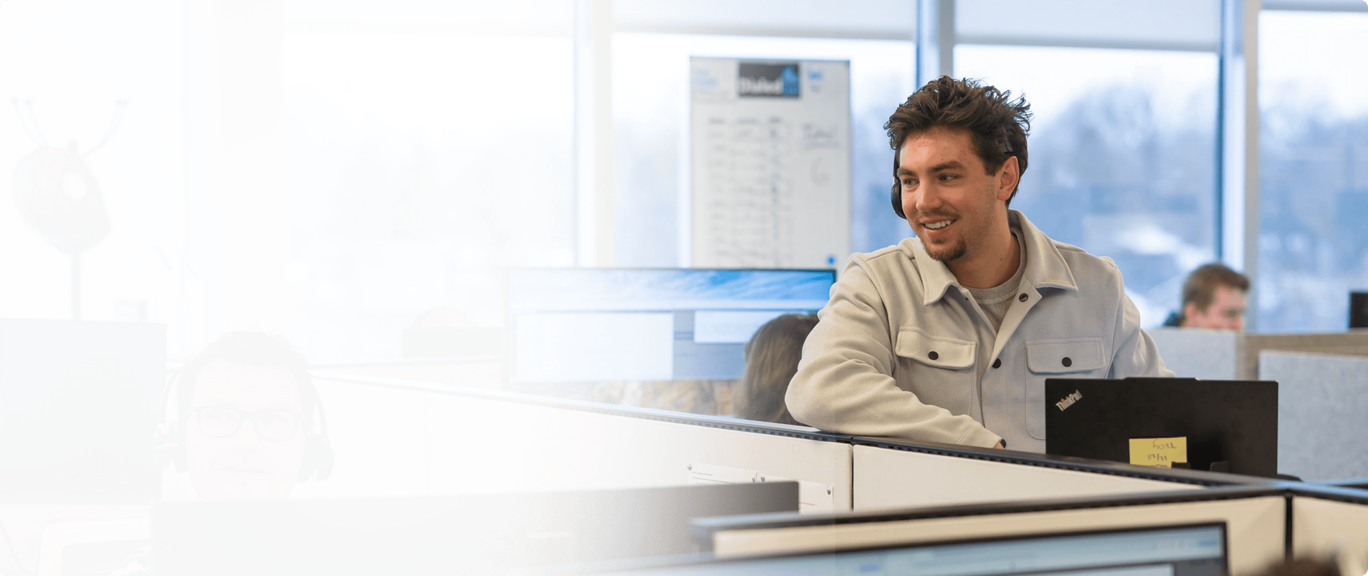A LitFinancial representative stands in a call center speaking with another representative who is out of view.
